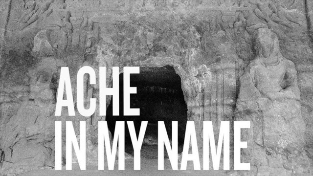 Pale grey rock, the heavily-eroded entrance to a temple, with a dark black opening. Overlaid in bold white text are the words ‘Ache In My Name’.