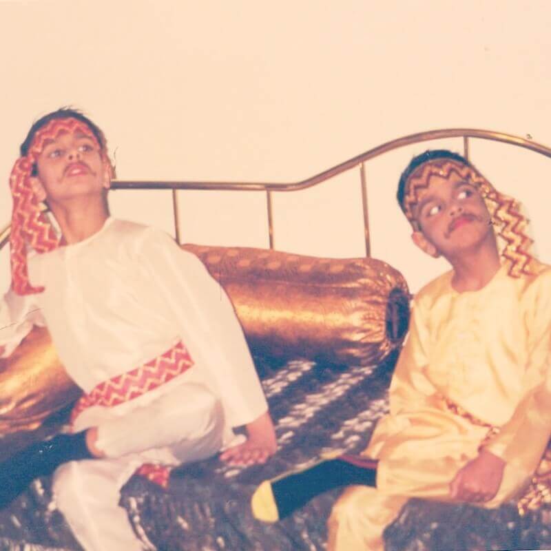 Vivek and Shamik, both several years older than the last picture, sitting on a daybed and dressed in similar Indian clothing.